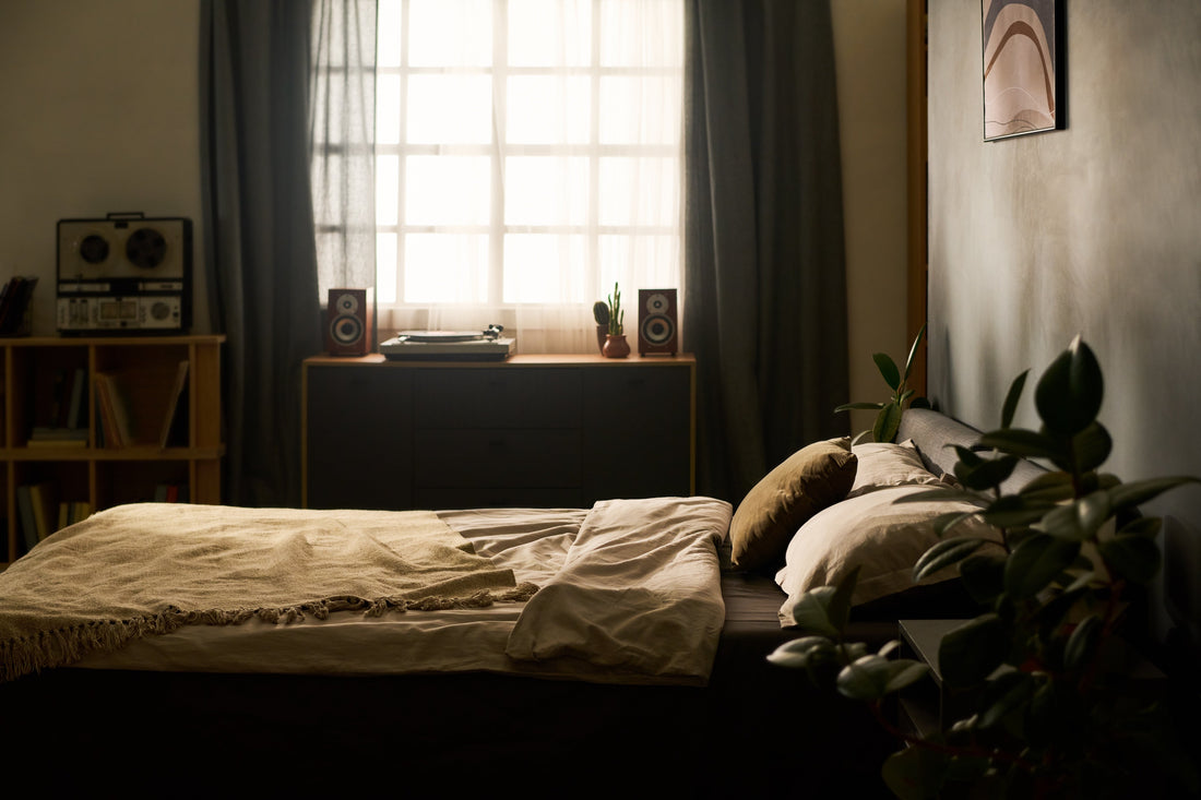 Early morning sunlight falling across a bedroom wall and an unmade bed