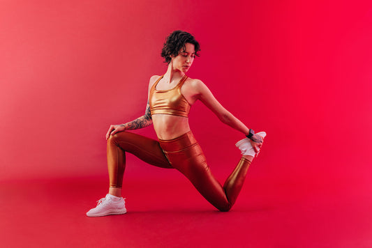 Woman in gold activewear stretching against a crimson background